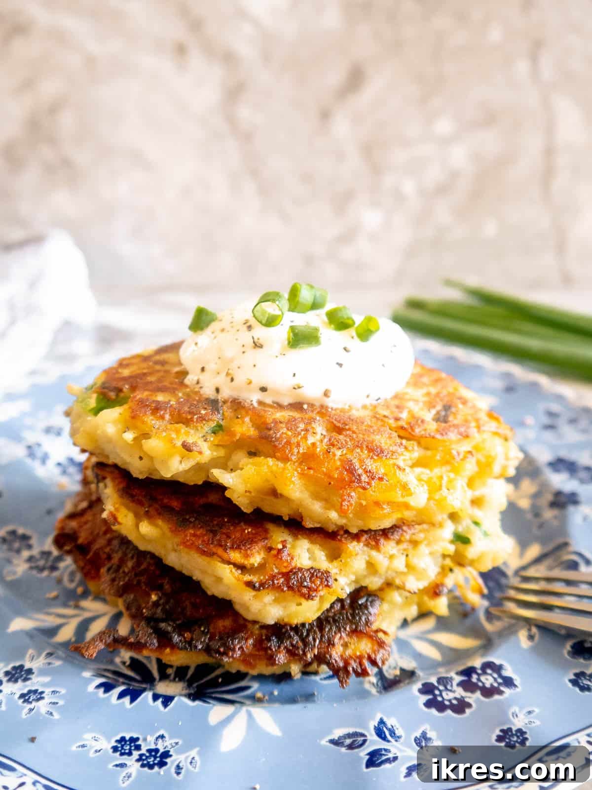 A stack of golden brown Whole30 potato pancakes on a white plate, showcasing their inviting texture.