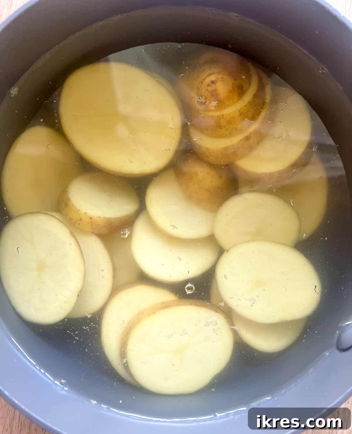 Half of the potatoes are sliced and placed in a pan filled with water, ready for boiling.