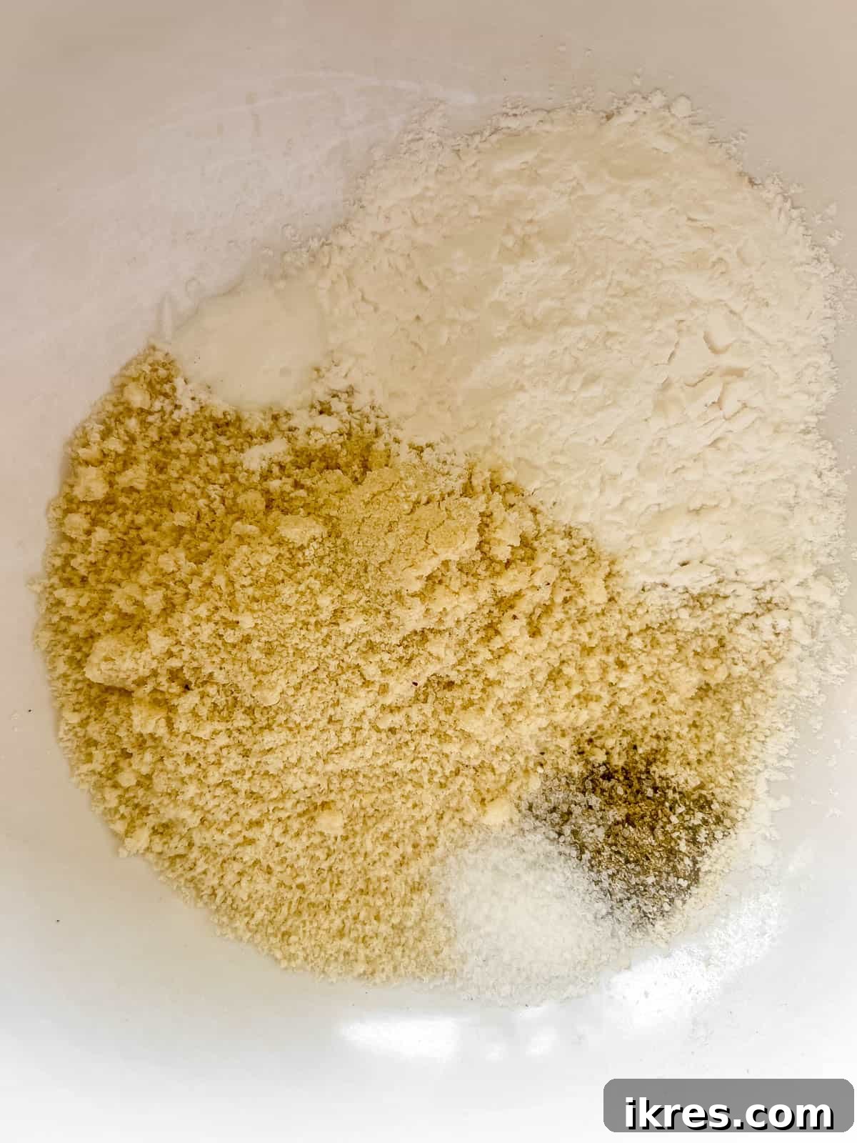 A small bowl containing almond flour, tapioca flour, baking soda, salt, and pepper, mixed together.