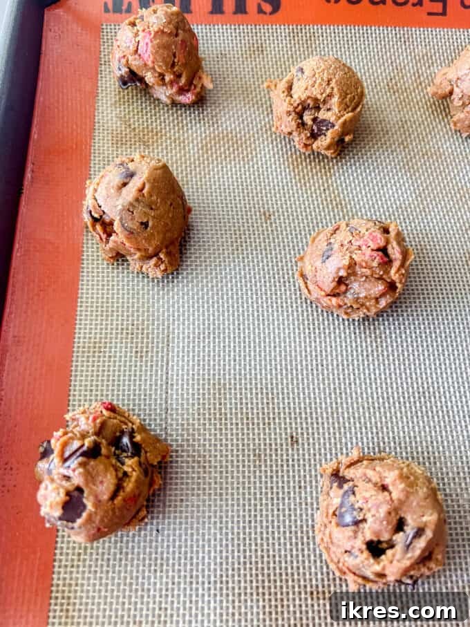 Strawberry Chocolate Chip Paleo Delights 10 Portioned cookie dough balls placed on a baking sheet lined with parchment paper.