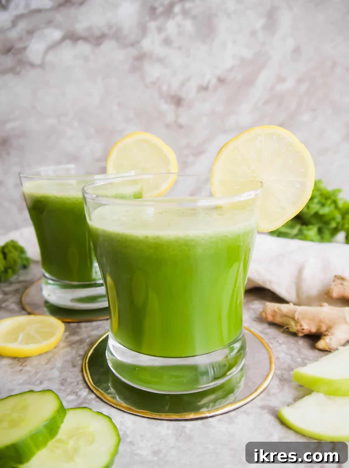 Fennel Ginger Green Elixir 5 Two pristine cups of Green Juice with Apple, Kale, Cucumber, Fennel, and Ginger, invitingly placed on a wooden surface.