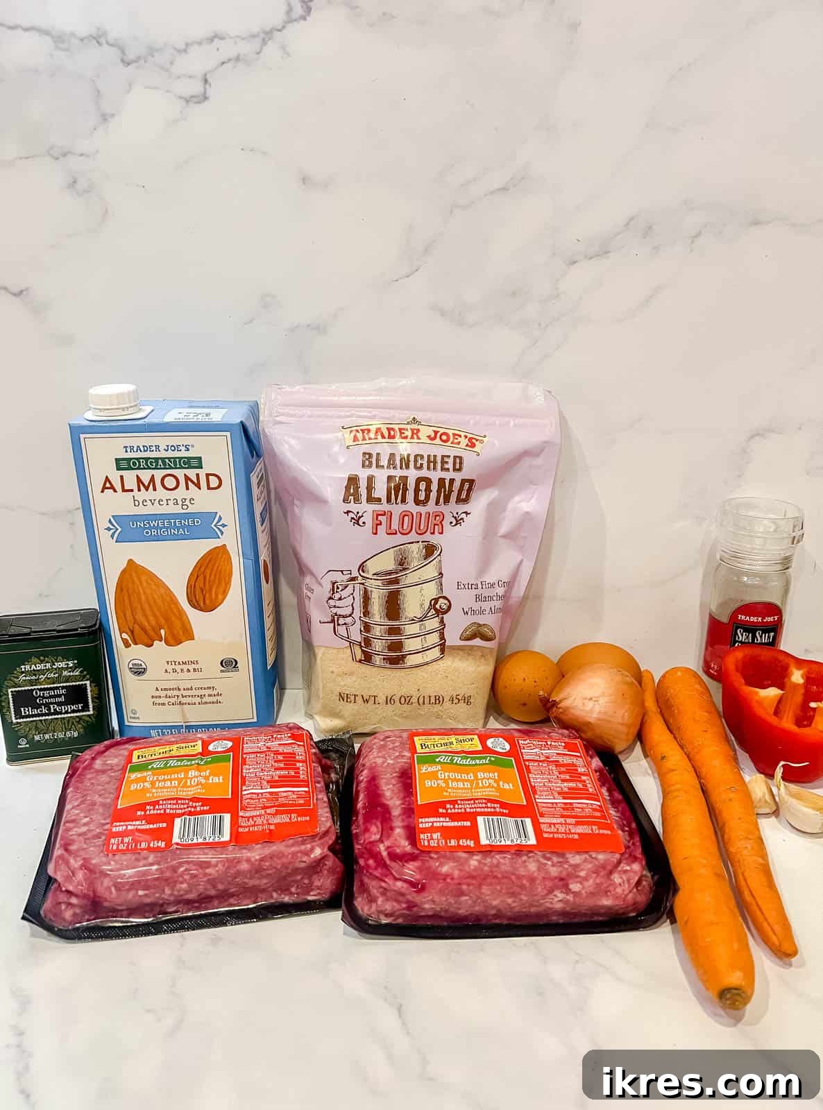 Primary ingredients for the paleo meatloaf, such as ground beef, almond flour, eggs, and fresh vegetables, neatly arranged.