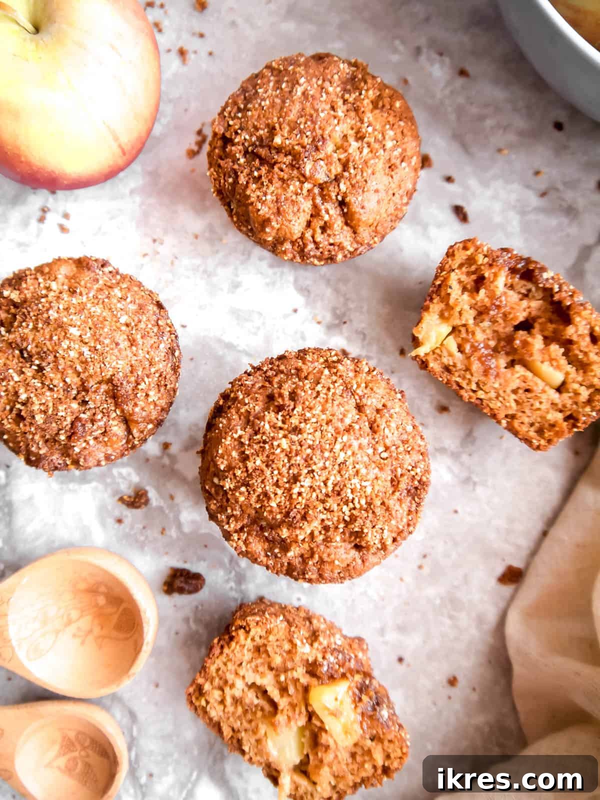 Nourishing Paleo Apple Muffins 4 Three paleo apple cinnamon muffins arranged artfully on a rustic wooden table.