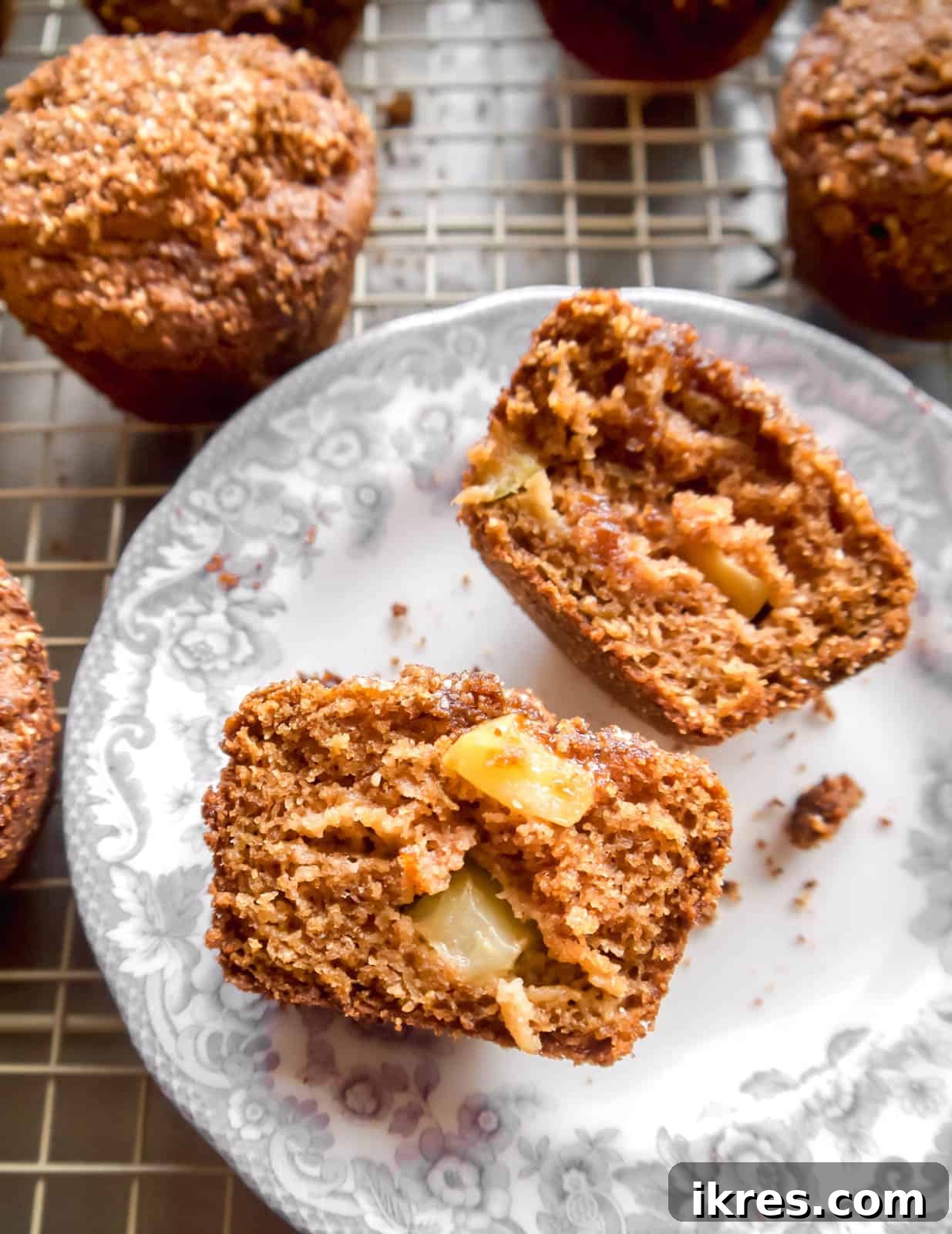 Nourishing Paleo Apple Muffins 6 A healthy gluten-free apple muffin cut in half on a plate, showing its moist interior.