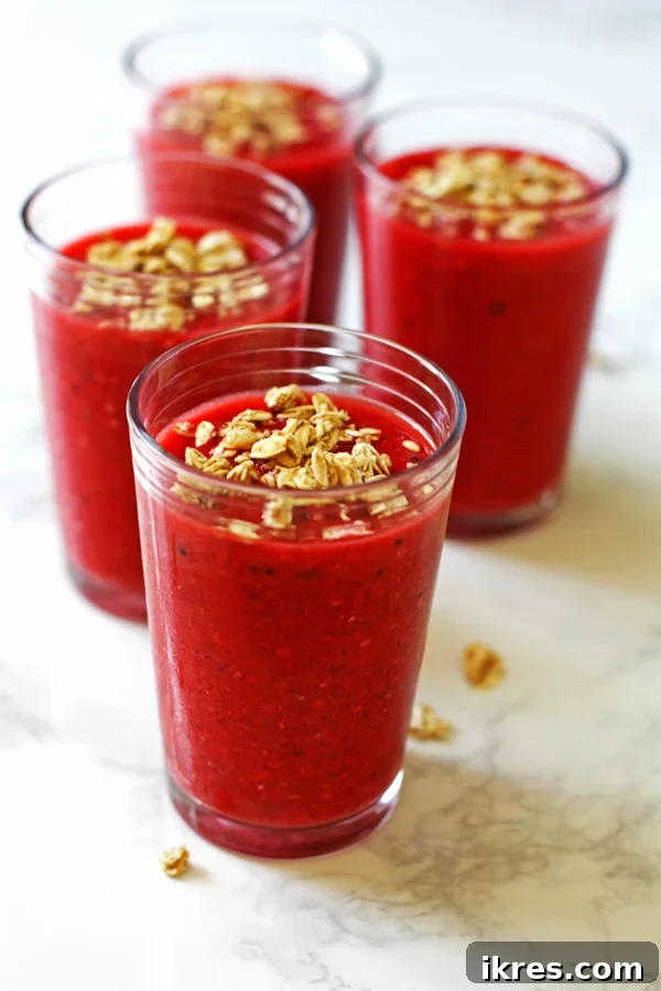 Morning Berry Granola Fuel 4 Four beautifully arranged mixed fruit and granola smoothies in clear glasses, garnished with fresh berries and a sprinkle of granola, ready for a healthy breakfast.
