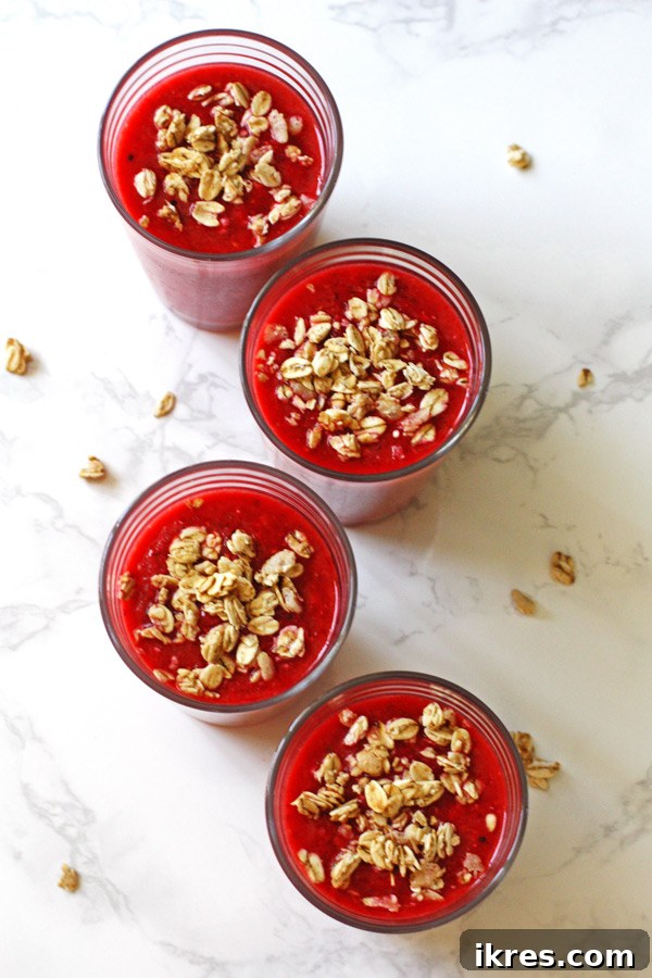 Morning Berry Granola Fuel 5 A vibrant mixed fruit and granola smoothie, garnished with fresh berries and a generous sprinkle of granola, set against a bright background.