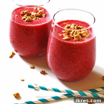 Two glasses of Berry Granola Smoothie, a healthy and quick breakfast option, garnished with fresh berries.