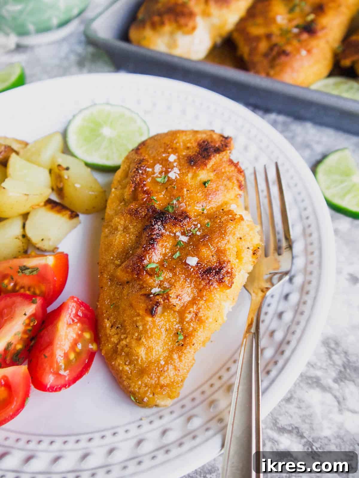 Almond flour breaded chicken with maple lime sauce, expertly sliced and arranged on a plate with fresh lime wedges and a sprig of cilantro for garnish.