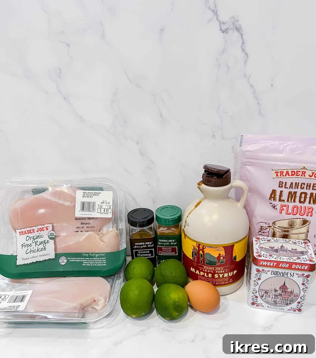 An array of fresh ingredients including chicken breasts, limes, maple syrup, almond flour, and spices, neatly arranged for making the maple lime chicken recipe.