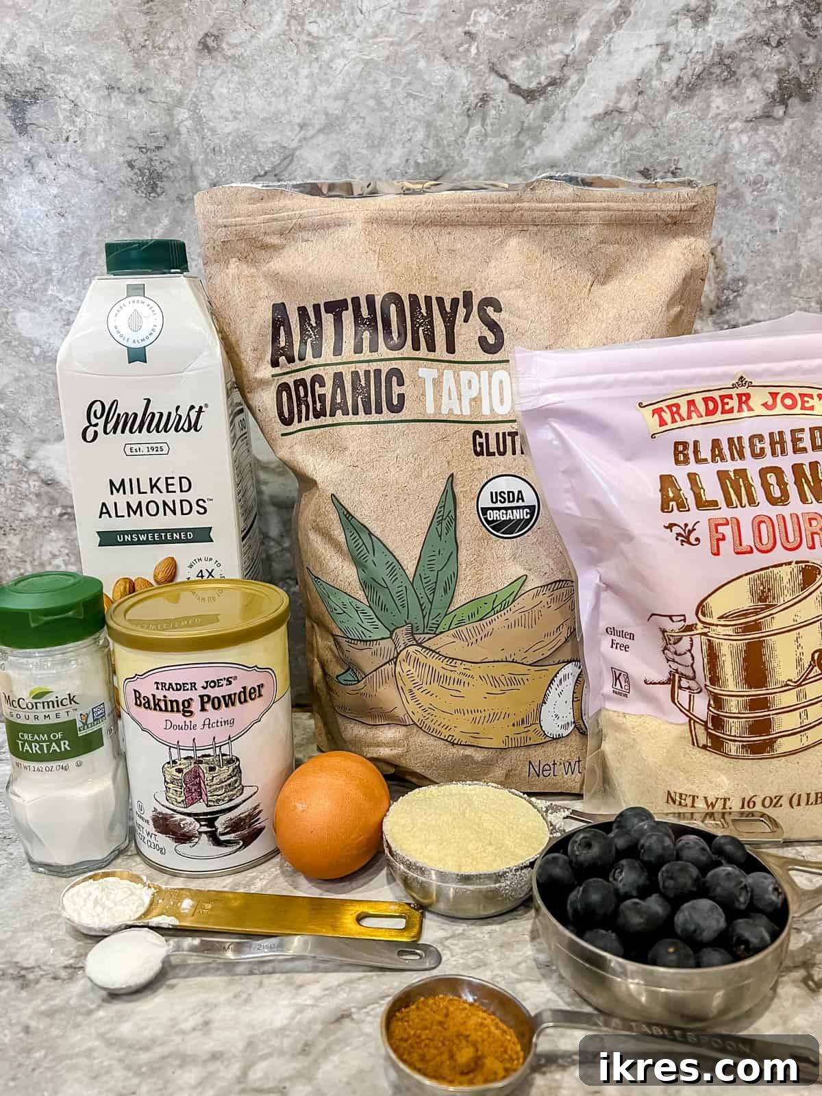 Fluffy Paleo Blueberry Pancakes 4 A collection of ingredients laid out on a table, including almond flour, tapioca flour, coconut flour, eggs, blueberries, and various liquids, ready for making Paleo blueberry pancakes.