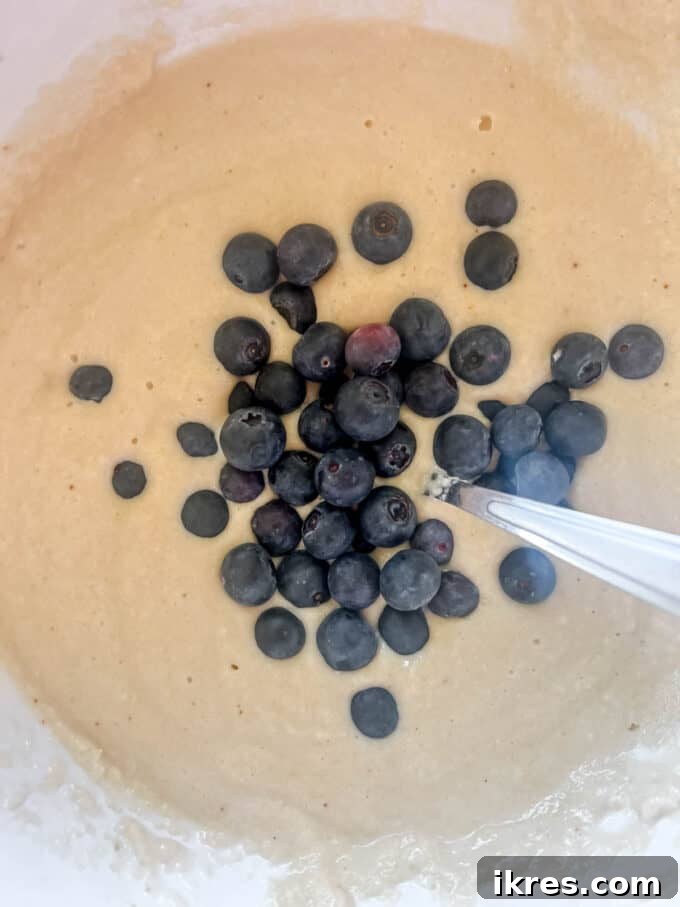 Fluffy Paleo Blueberry Pancakes 9 Fresh blueberries freshly added to the Paleo pancake batter in a bowl, awaiting folding.