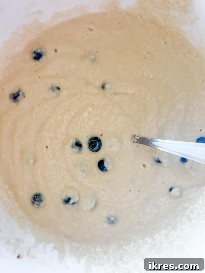 Fluffy Paleo Blueberry Pancakes 10 Blueberries carefully folded into the Paleo pancake batter, ensuring even distribution without crushing them.