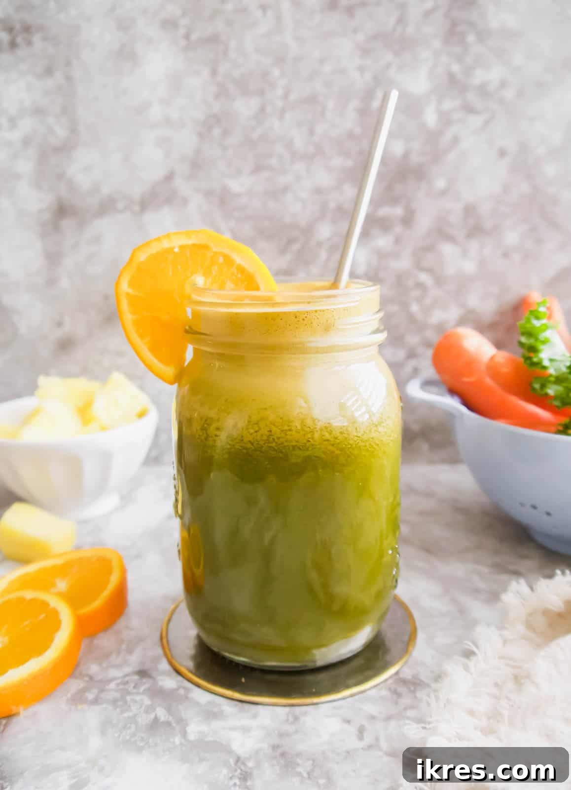 A close-up shot of Kale Carrot Juice in a mason jar with a straw, showcasing its vibrant color and freshness.
