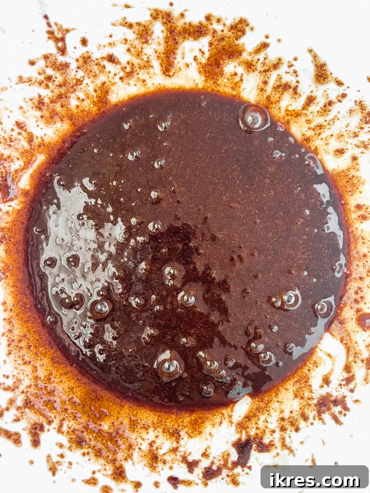 A bowl containing wet ingredients for Paleo chocolate chip cookies, including melted coconut oil, coconut sugar, egg, and vanilla extract, perfectly mixed together.
