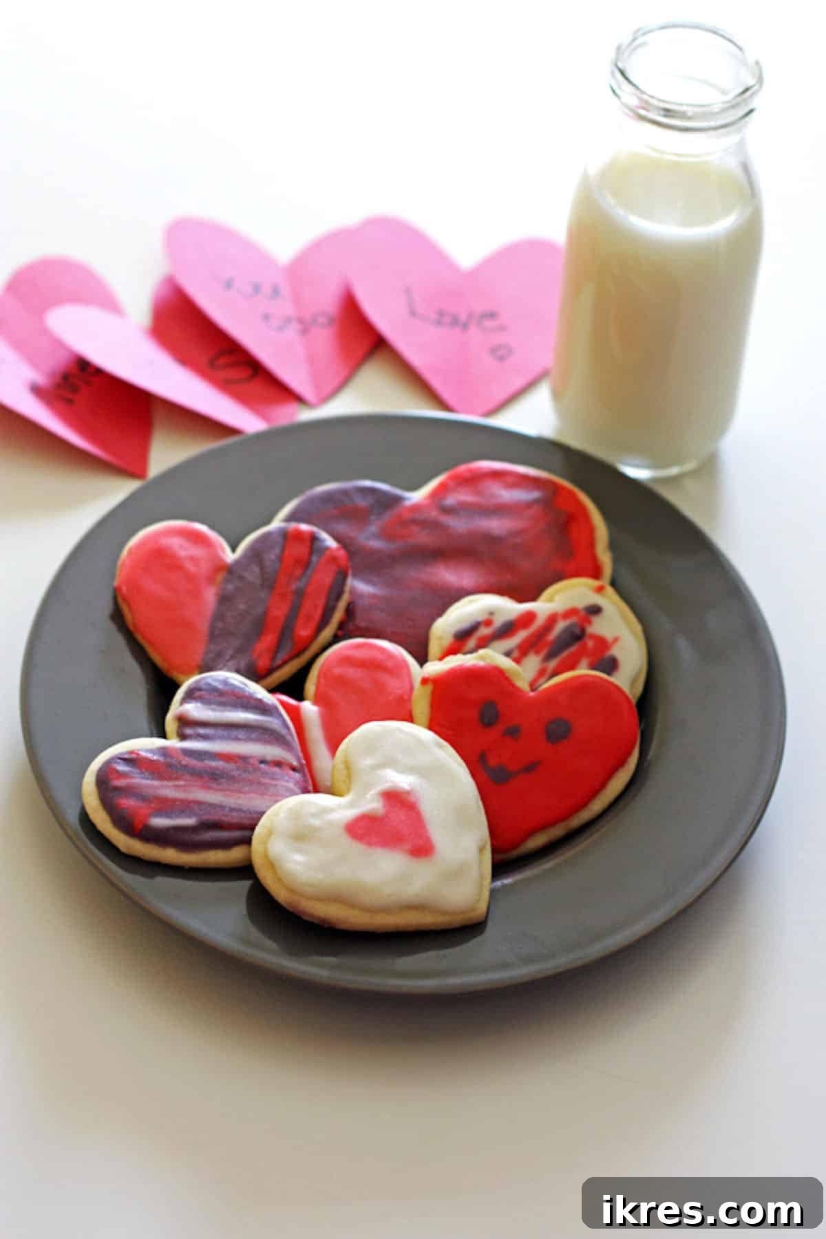 A plate of exquisitely frosted heart cookies, ready to be enjoyed with a refreshing glass of milk.