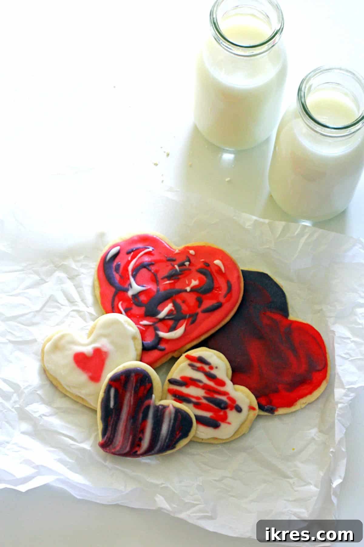 A festive pile of heart-shaped sugar cookies, accompanied by two glasses of milk, perfect for sharing.