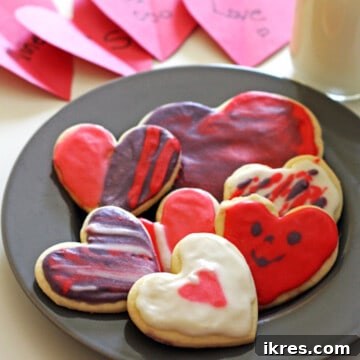 A plate of festive frosted heart cookies, accompanied by romantic cards and a glass of milk.