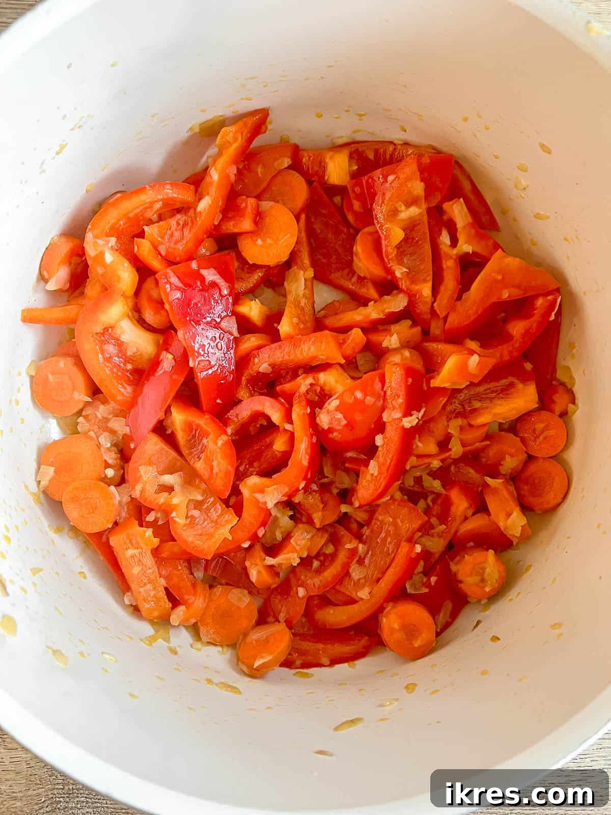 Plant-Based Paleo Thai Red Curry 5 Adding colorful sliced bell peppers and carrots to the pan to sauté with the aromatics, creating a vibrant mix.