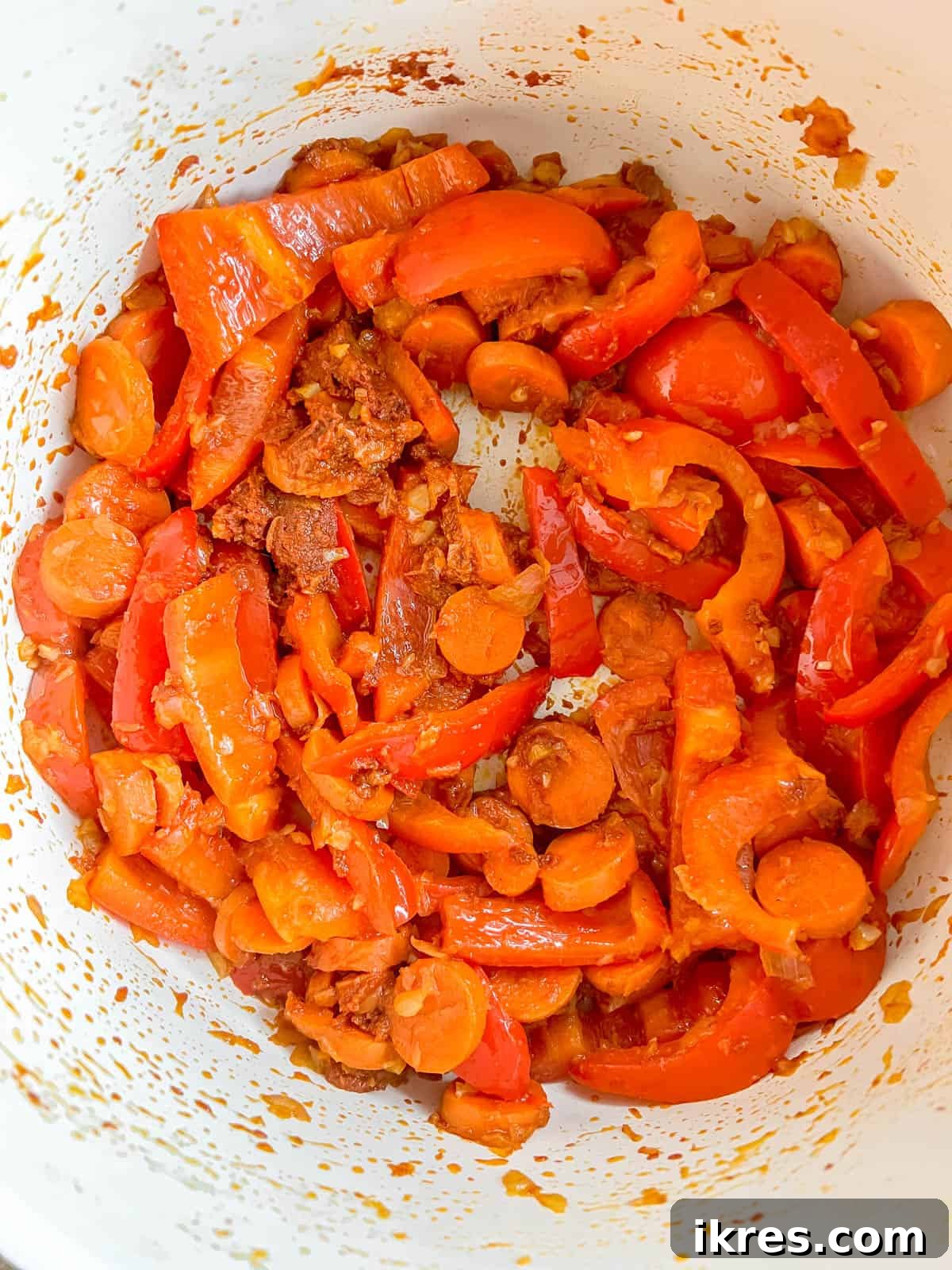 Plant-Based Paleo Thai Red Curry 6 Stirring in rich red curry paste and fresh grated ginger with the vegetables in the pan, building complex flavors.