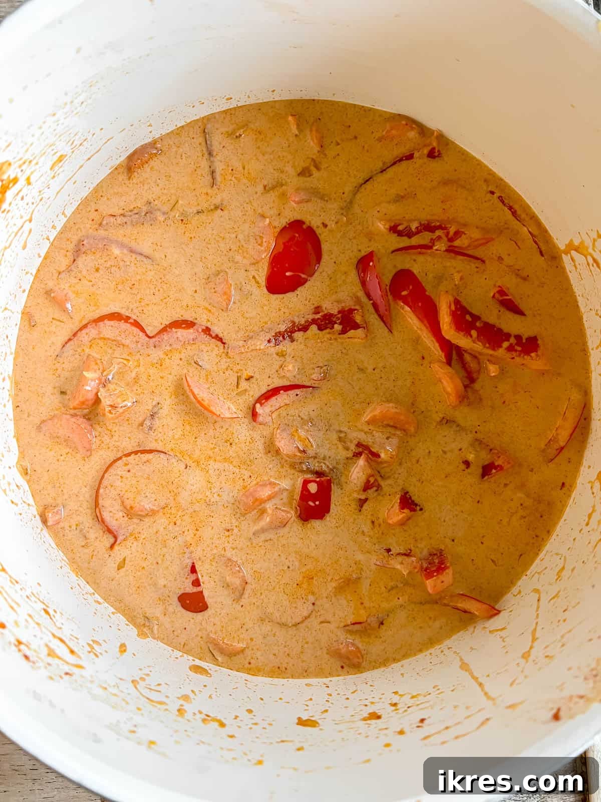 Plant-Based Paleo Thai Red Curry 7 Pouring a generous amount of creamy coconut milk into the pan, forming the luscious base of the Thai red curry.