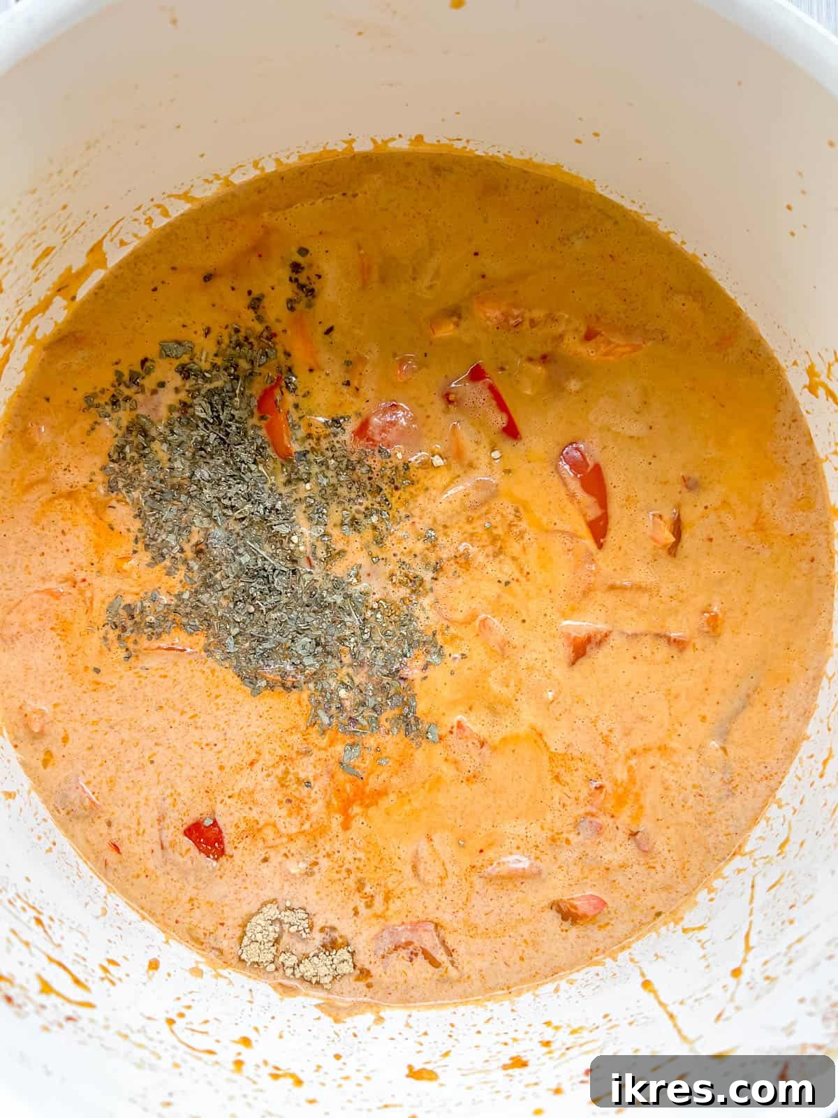 Plant-Based Paleo Thai Red Curry 8 Adding various seasonings including dried basil and ground ginger to the simmering paleo Thai red curry sauce.