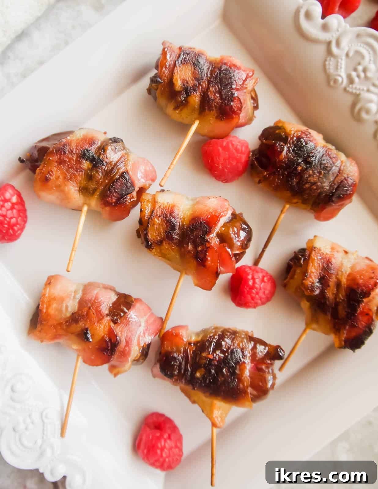 Blissful Bacon Wrapped Raspberry Date Bites 8 A batch of freshly baked raspberry stuffed dates, wrapped in crispy, golden-brown bacon, cooling on a baking sheet.