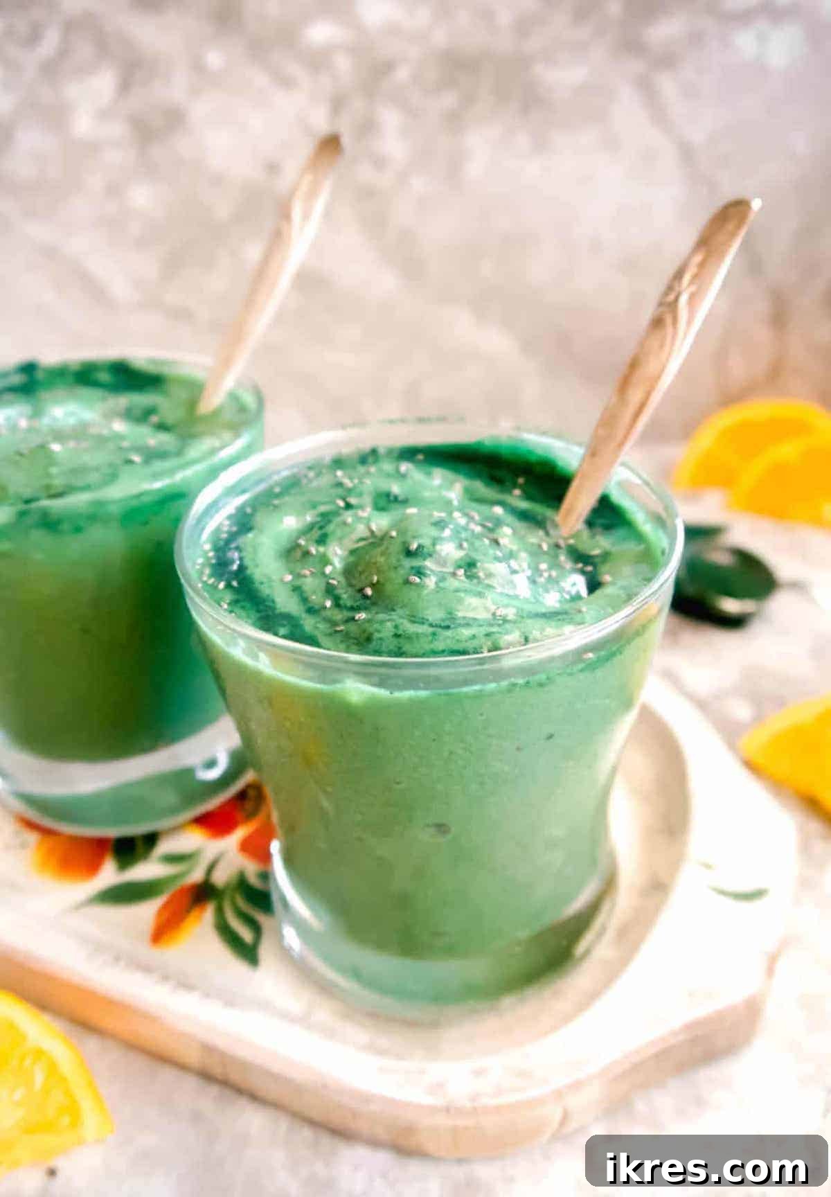 Sunrise Spirulina Fusion 3 A refreshing spirulina smoothie served in two elegant glasses, with fresh orange slices delicately placed in the soft-focus background, highlighting the citrus notes of the drink.