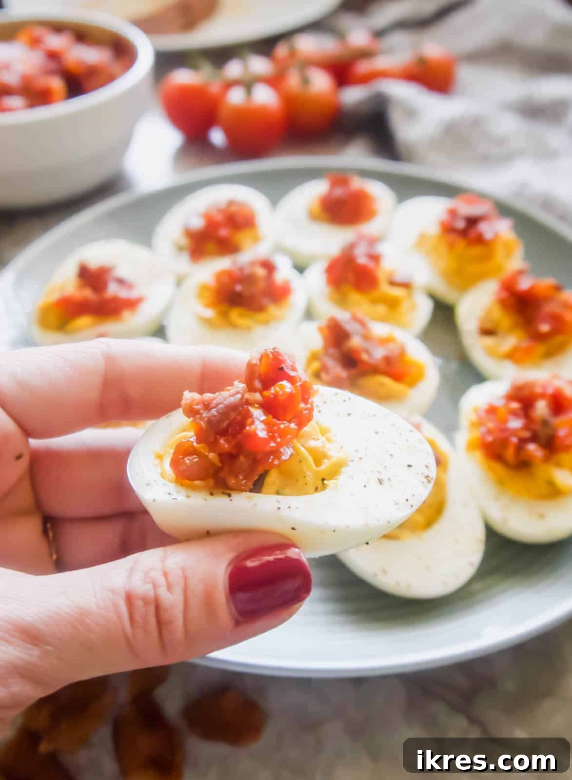 Beautifully presented Paleo Deviled Eggs with a generous dollop of homemade Tomato Bacon Jam.
