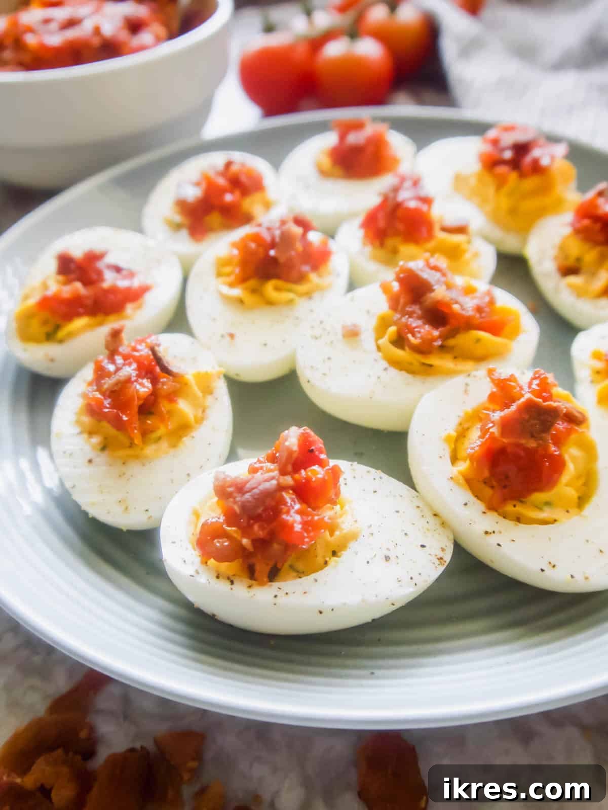 Close-up of creamy Paleo Deviled Eggs garnished with vibrant Tomato Bacon Jam.