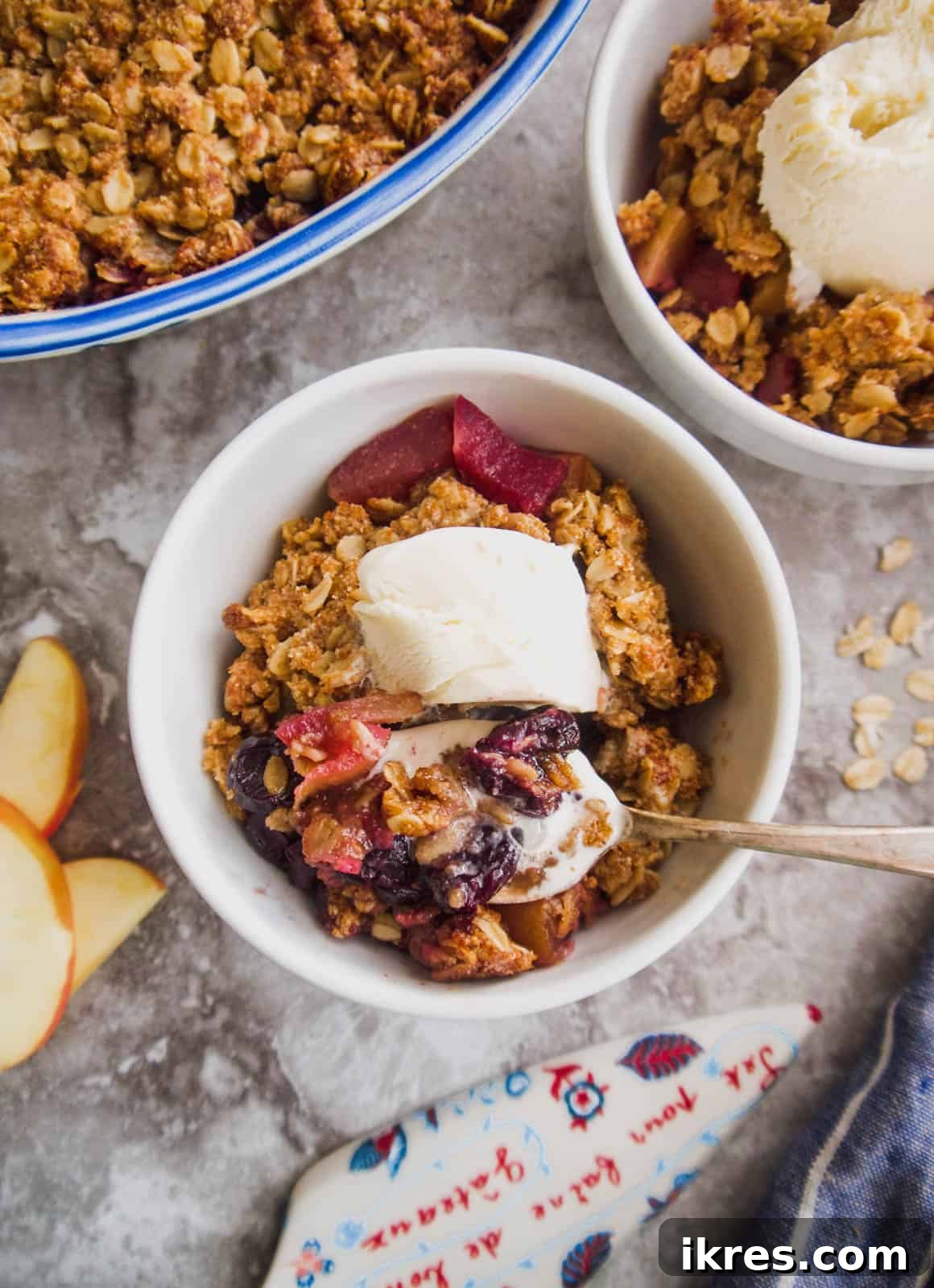 Wholesome Gluten Free Vegan Apple Cherry Bake 4 Two bowls of vegan apple cherry crisp with scoops of vanilla ice cream melting on top, garnished with a fresh cherry.
