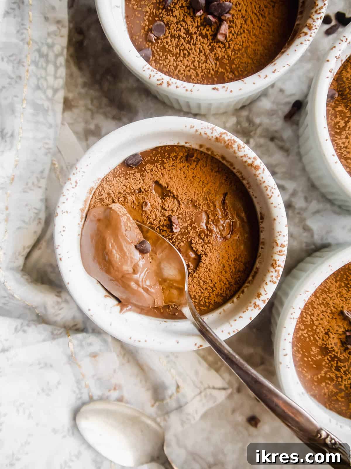 Indulgent Paleo Vegan Chocolate Pudding 4 A spoon scooping creamy vegan chocolate pudding from a ramekin.