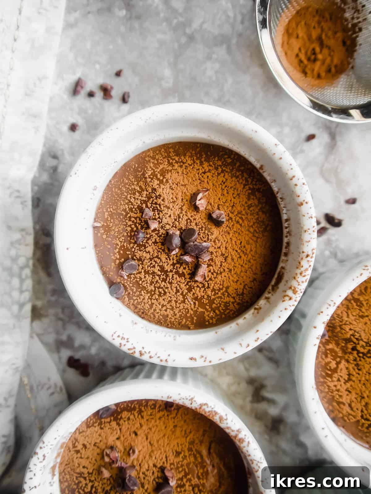 Indulgent Paleo Vegan Chocolate Pudding 6 Ramekins of dairy-free chocolate pudding garnished with chocolate chips.