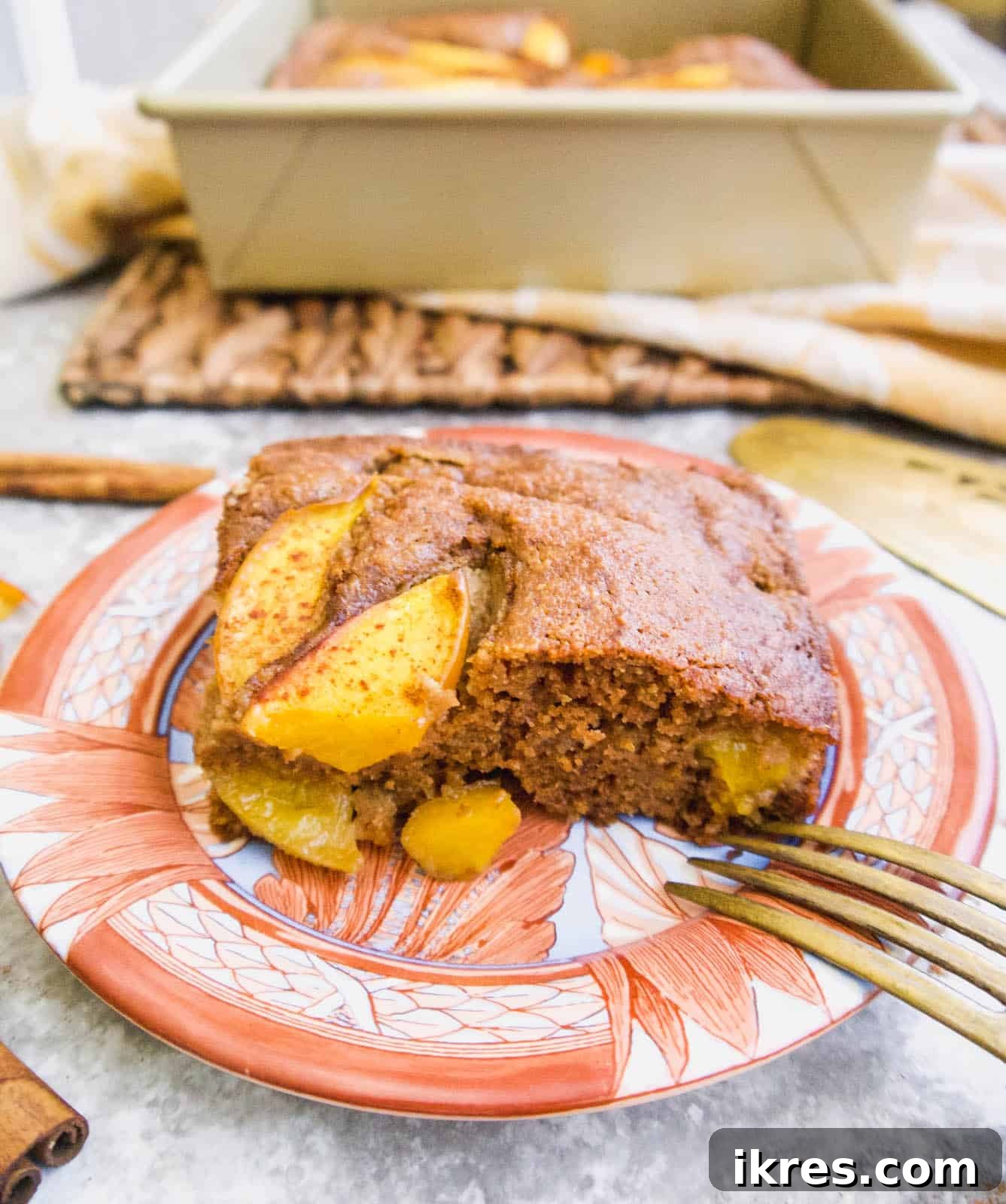 Primal Nectarine Banana Dream Cake 3 A perfectly sliced piece of gluten-free nectarine banana cake on a white plate, revealing its moist interior and fruit swirls.