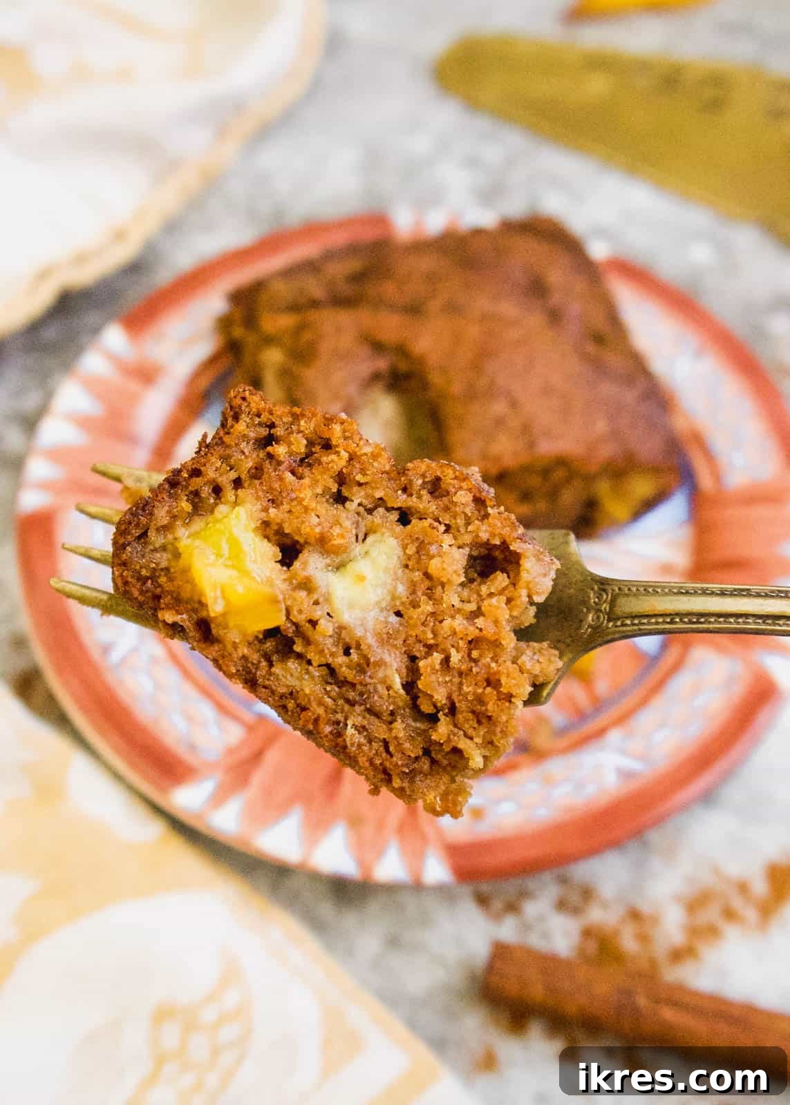 Primal Nectarine Banana Dream Cake 4 A fork piercing a soft piece of gluten-free banana nectarine bread, showing its moist and tender texture.