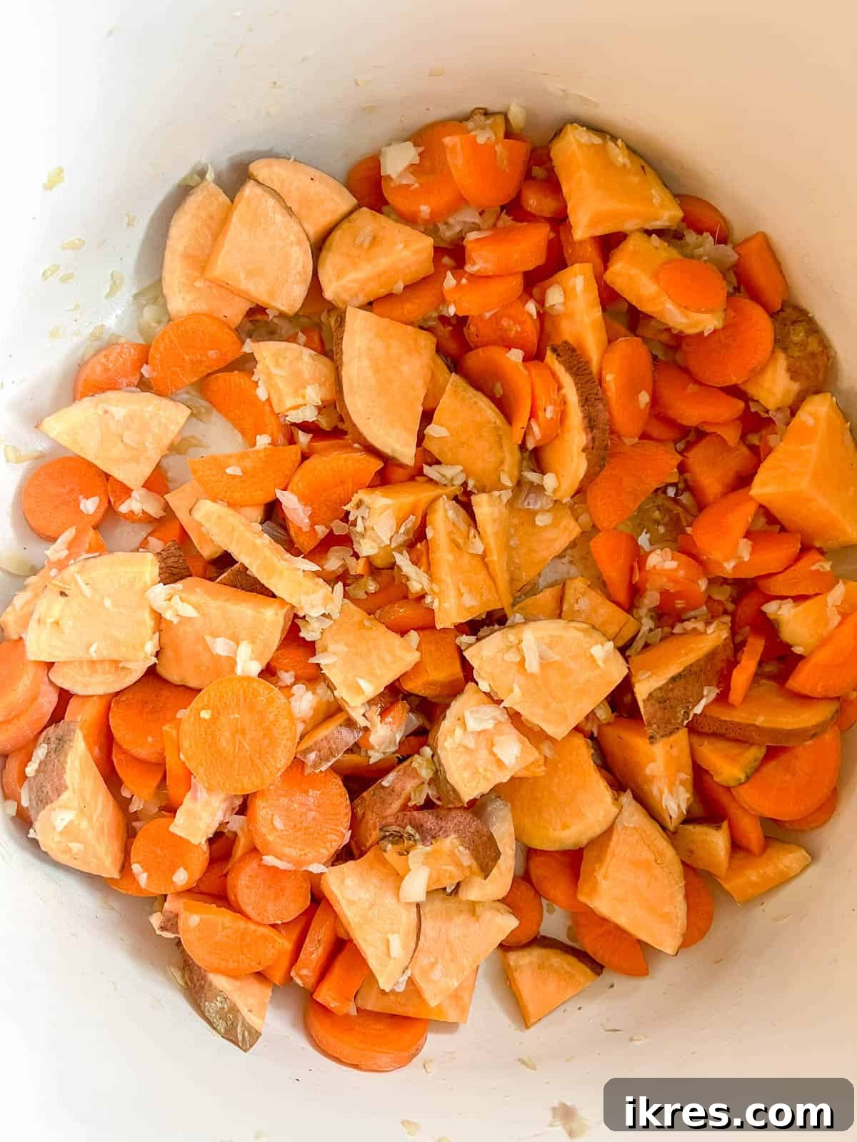 Zesty Dairy-Free Chicken Bake 6 Thinly sliced carrots and sweet potatoes cooking in a pan with sautéed onions and garlic.