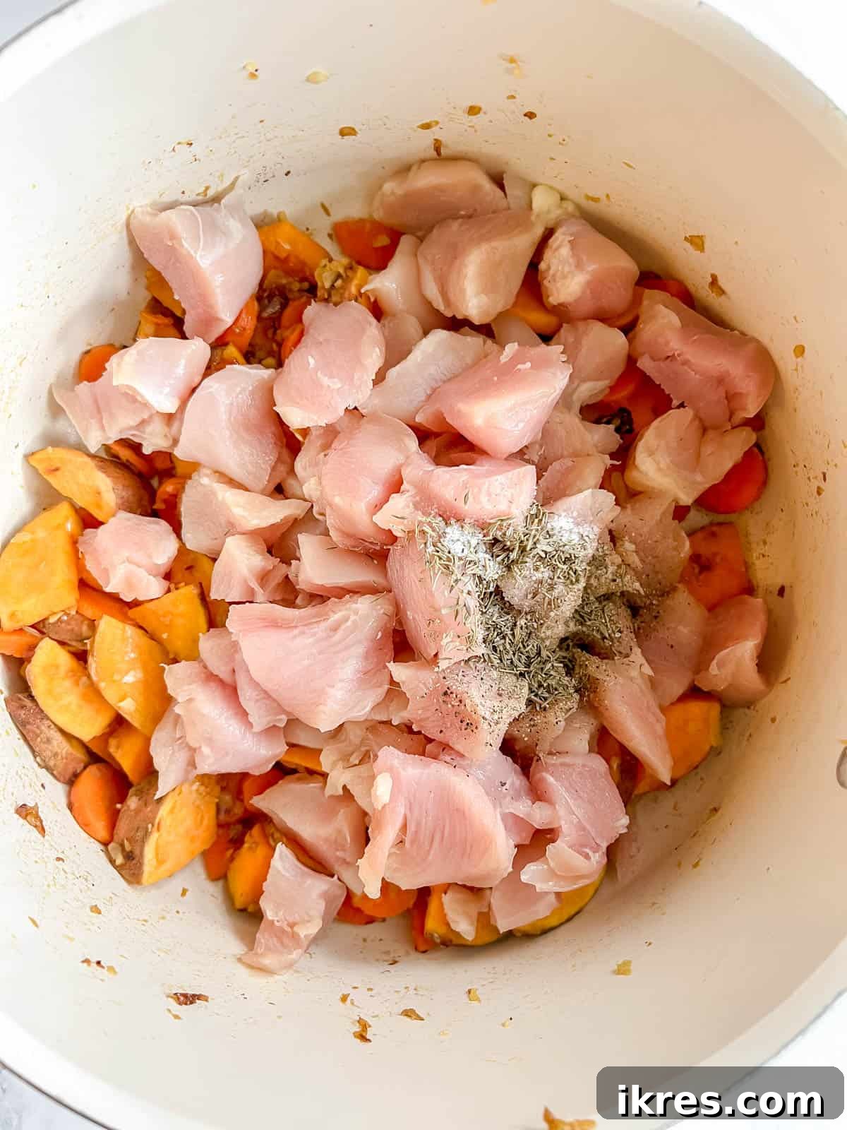 Zesty Dairy-Free Chicken Bake 7 Diced chicken and dried spices, including thyme, salt, and pepper, added to the pan with vegetables.