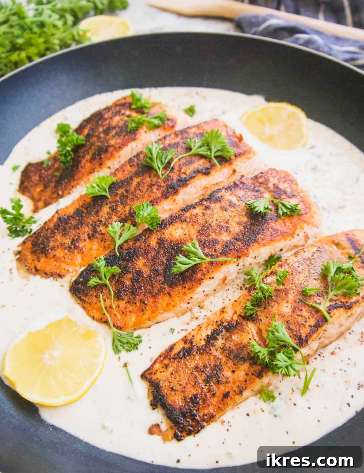 Crispy salmon sizzling in a pan, surrounded by a rich coconut cream sauce.