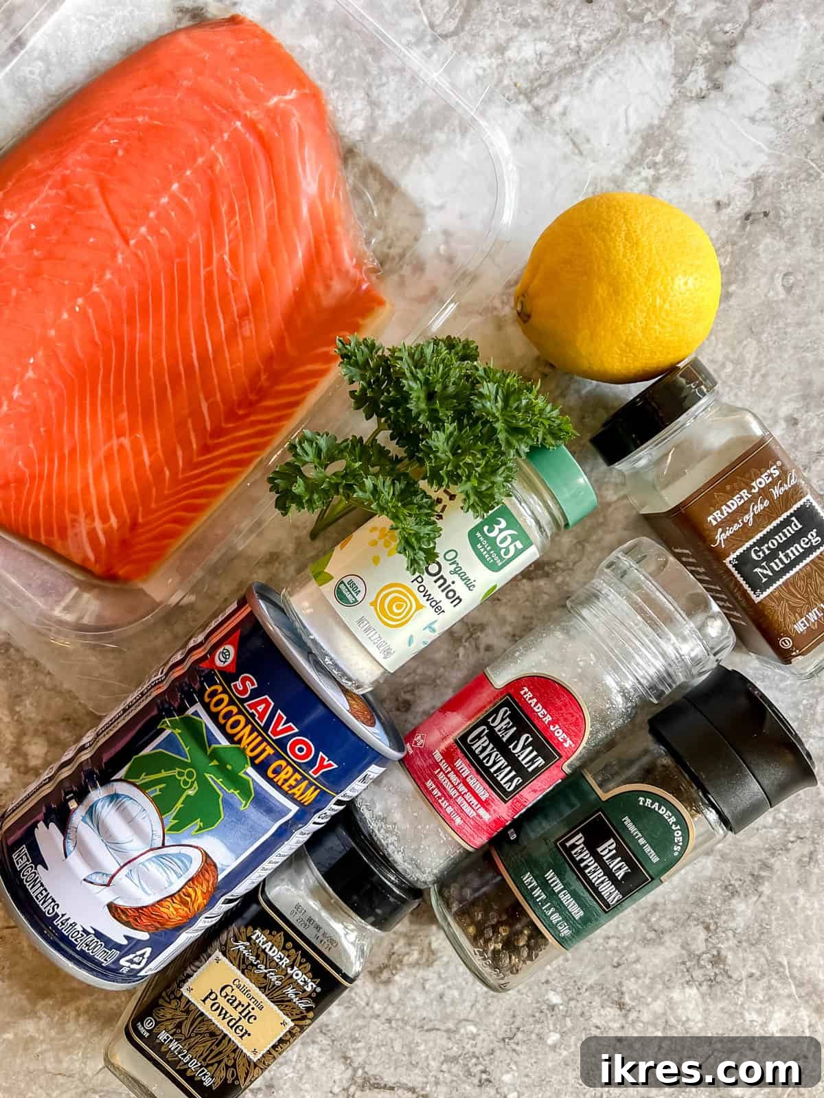 A selection of ingredients laid out, including salmon fillets, lemons, parsley, and a can of coconut cream.