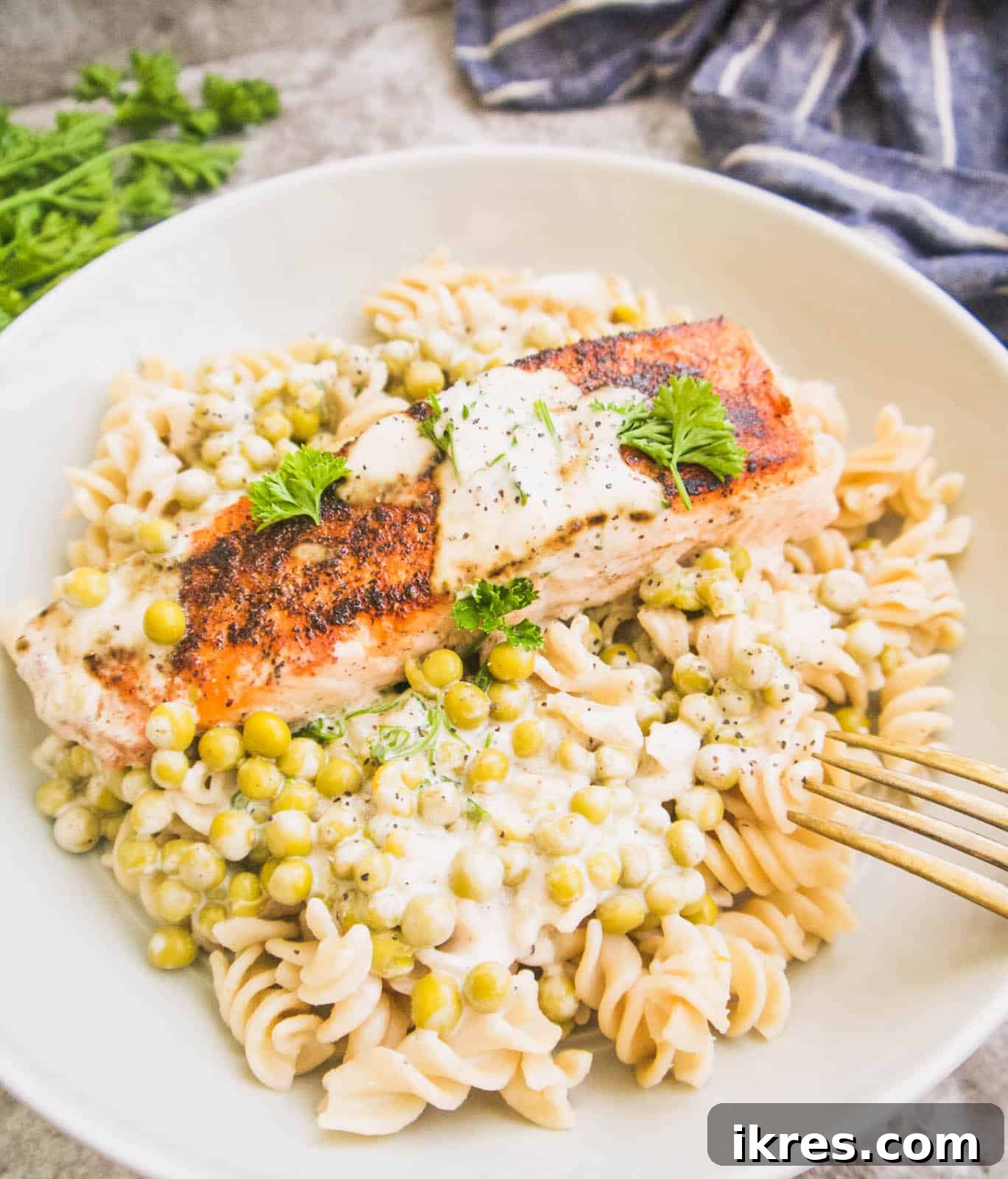 A bowl of Paleo salmon served with a creamy coconut sauce and vibrant green peas.