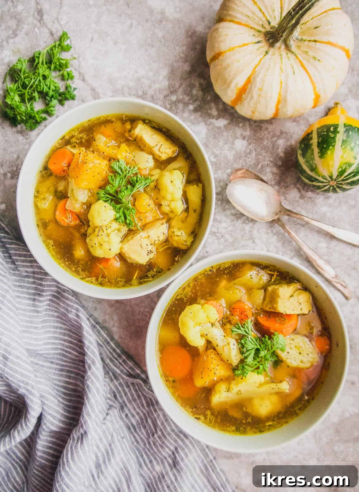 Two bowls of delicious Whole30 chicken soup artfully arranged on a rustic table.