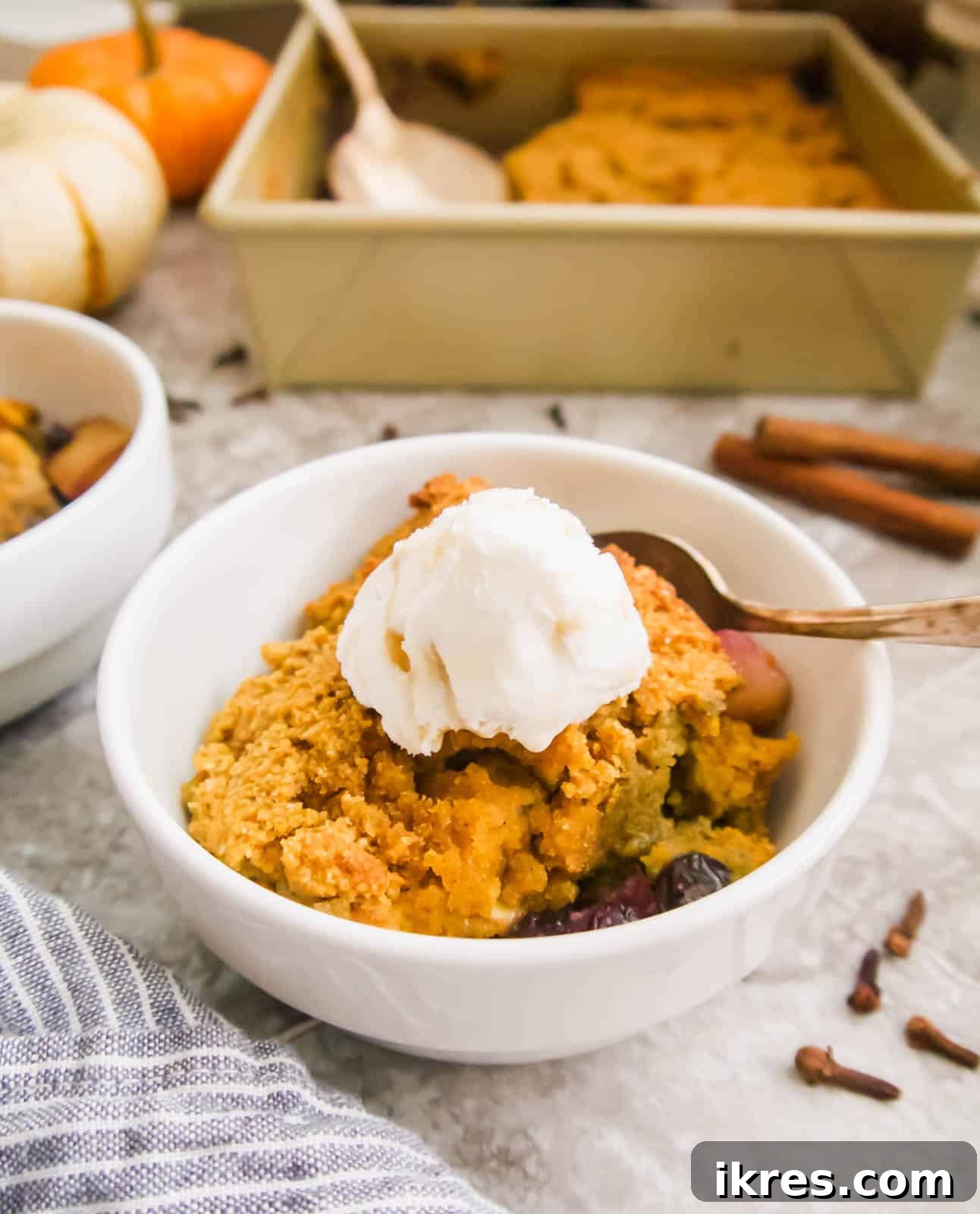 A full baking dish of Paleo Blueberry Pear Cobbler with a serving removed, showcasing the bubbly fruit and golden topping.