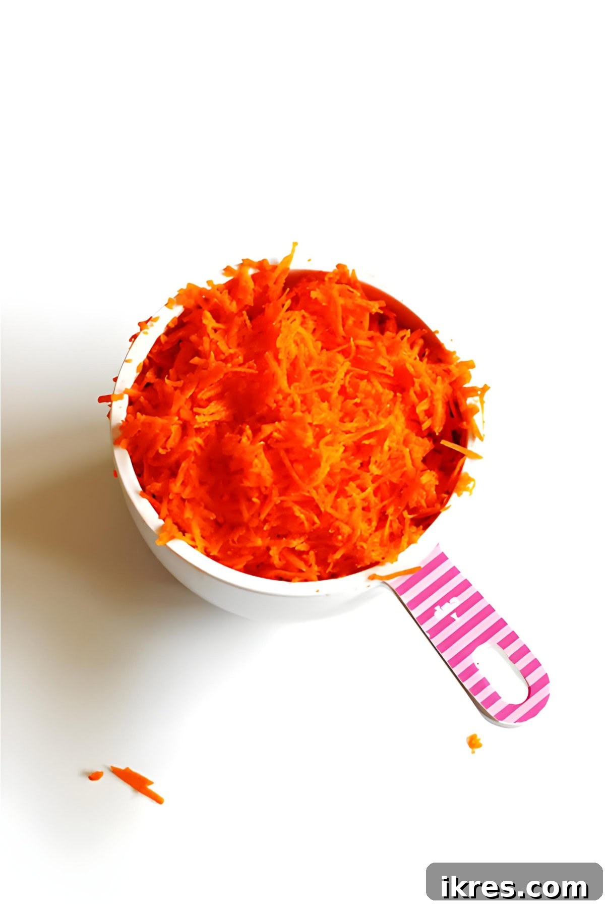 Perfectly Spiced Carrot Cake Muffins with Cream Cheese Glaze 3 Shredded carrots in white and pink measuring cup