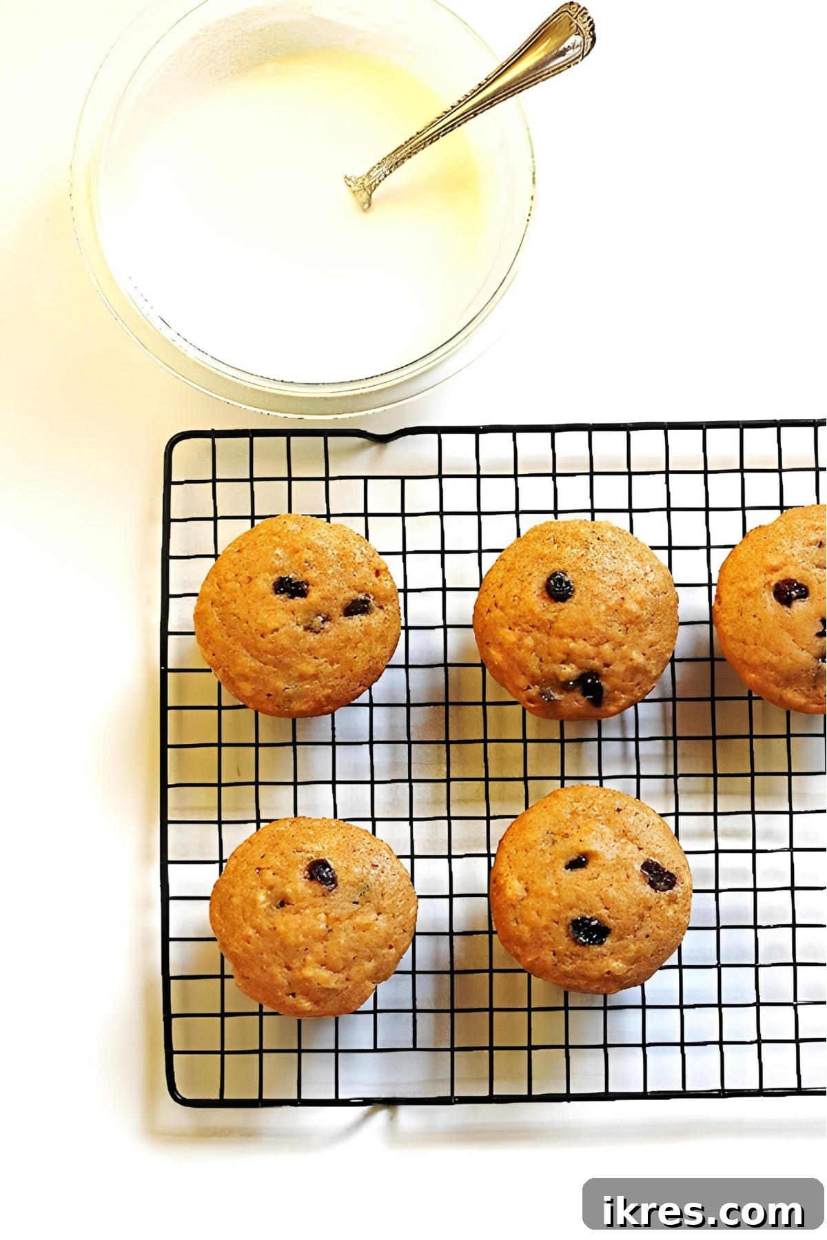 Perfectly Spiced Carrot Cake Muffins with Cream Cheese Glaze 6 Muffins on a cooling rack with the glaze in a bowl next to them