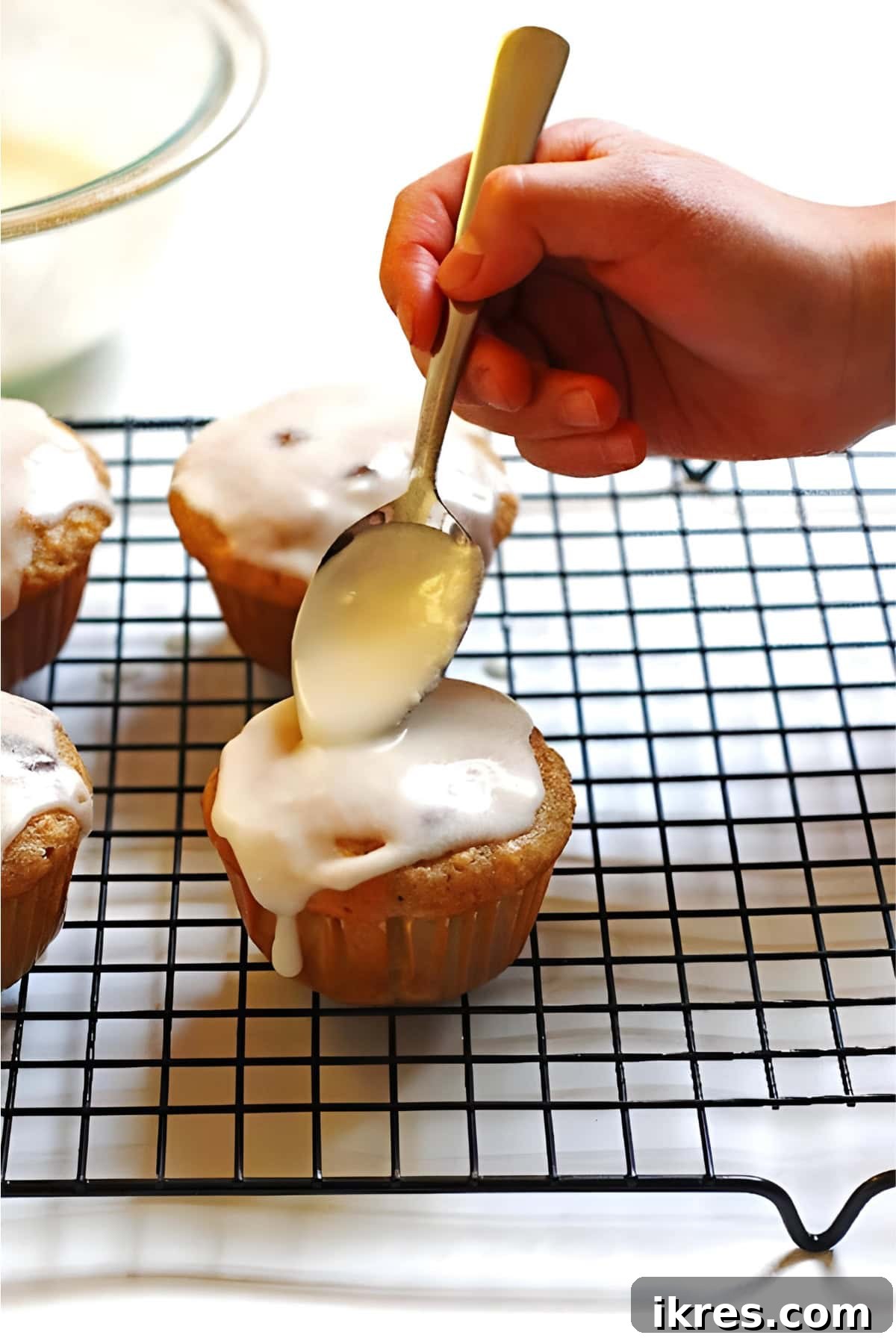 Perfectly Spiced Carrot Cake Muffins with Cream Cheese Glaze 8 Using the back of a spoon to spread the glaze around on a muffin