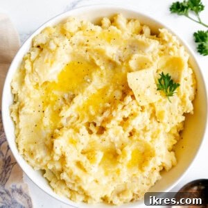 Creamy Garlic Cauliflower and Potato Mash in a bowl with butter and parsley on top.