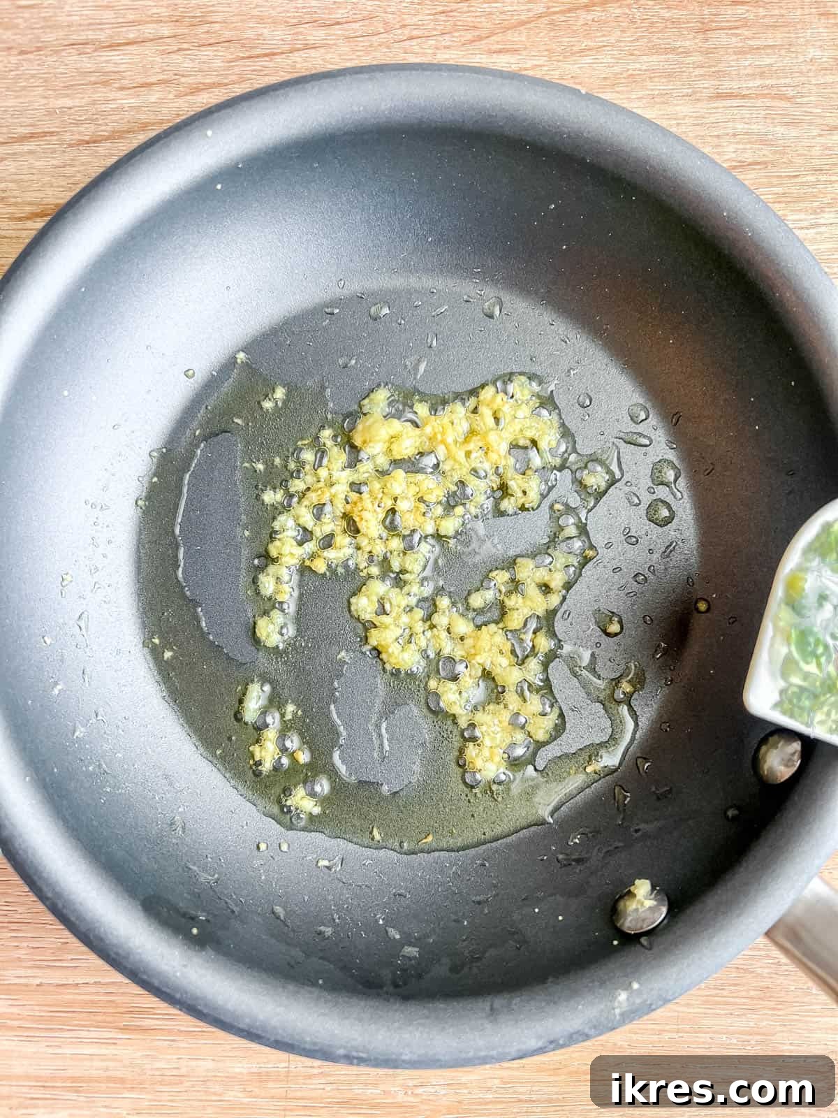 Minced garlic cloves gently sautéing in a pan with a splash of olive oil, releasing their aromatic fragrance.