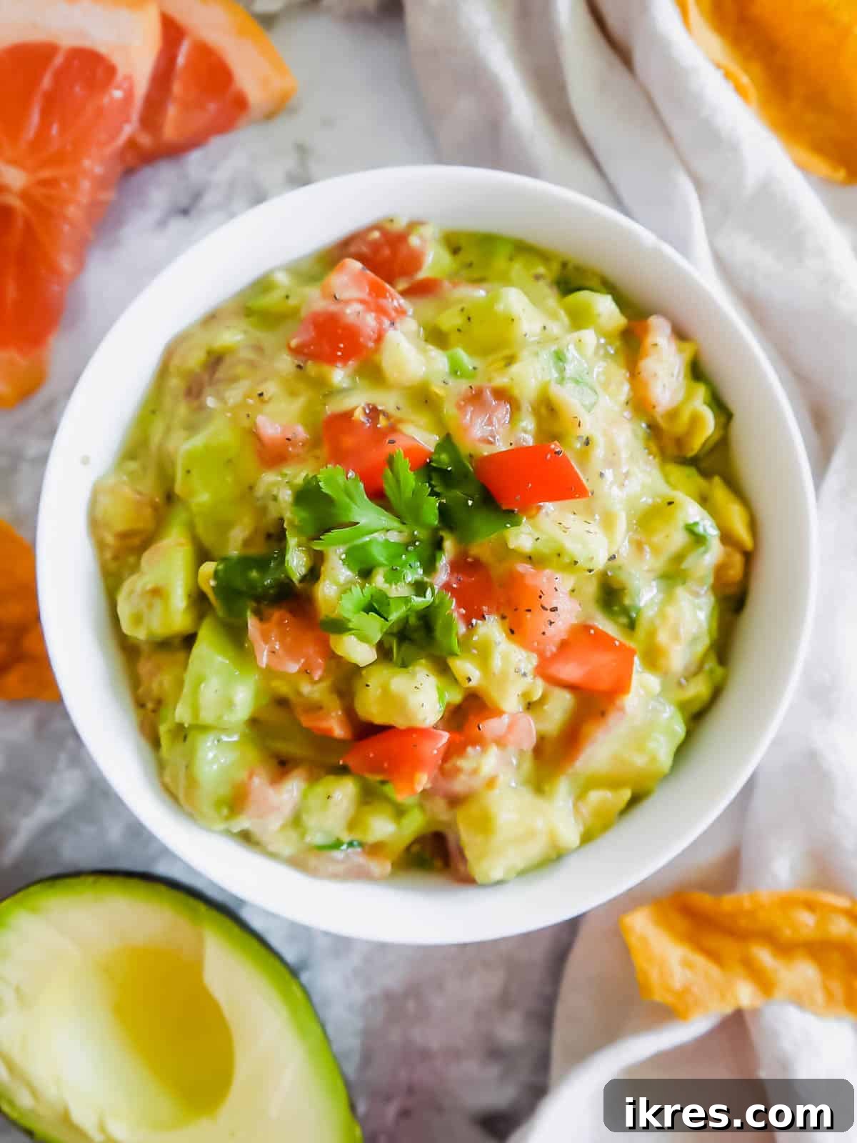 A large bowl filled to the brim with vibrant Grapefruit Guacamole, ready for sharing at a gathering.