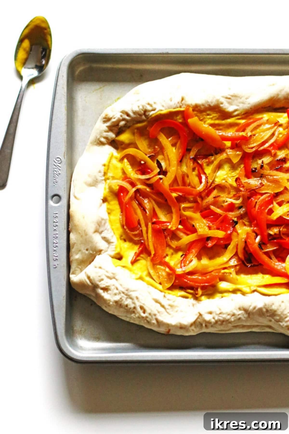 Supreme Pizza Perfection 4 Sliced peppers and onion over mustard on pizza dough placed a baking pan