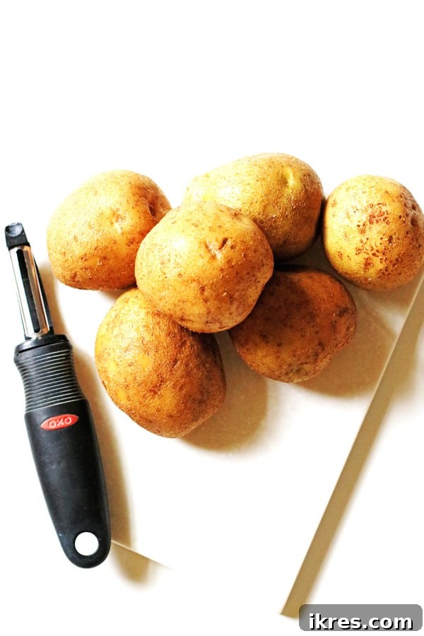 Golden Mashed Potato Bake 3 Potatoes on cutting board with a peeler