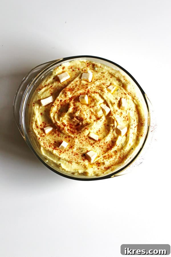 Golden Mashed Potato Bake 5 Mashed potatoes in a round pyrex dish dotted with butter and paprika sprinkled over them